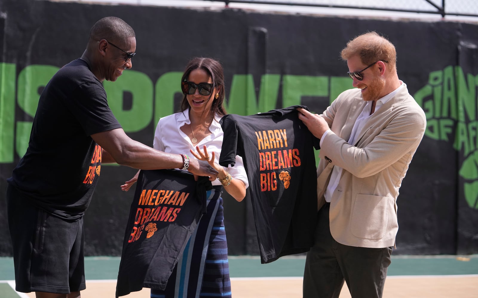 FILE - Masai Ujiri, Toronto Raptors President, left, presents T-Shirts to Prince Harry, right, and Meghan, center, during a basketball clinic hosted by the Giants of Africa Foundation in Lagos Nigeria, May 12, 2024. (AP Photo/Sunday Alamba, File)