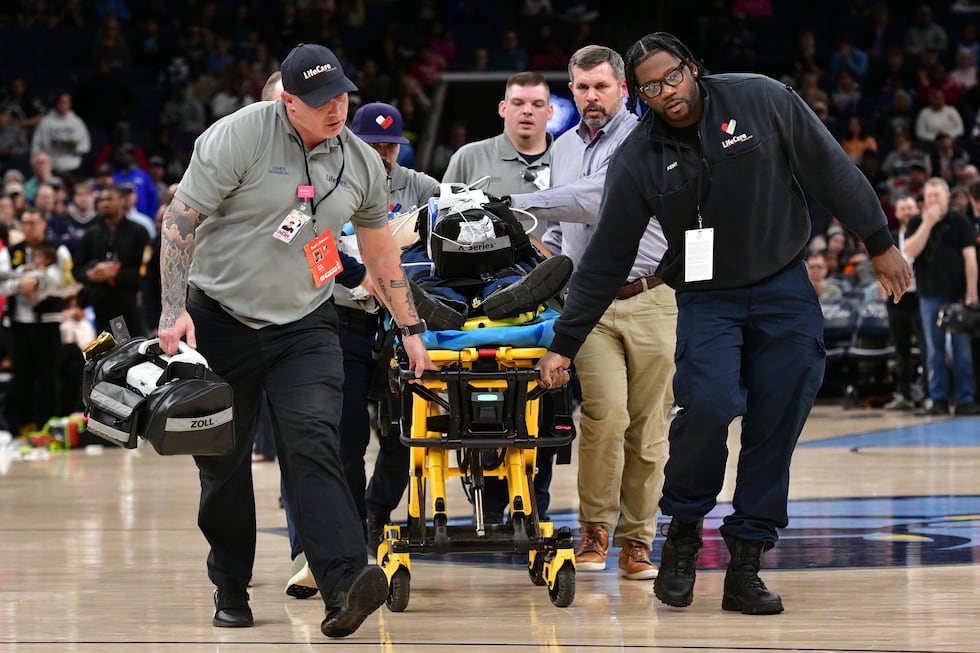 Medical personnel wheel a man off of the court after he collapsed before an NBA basketball...