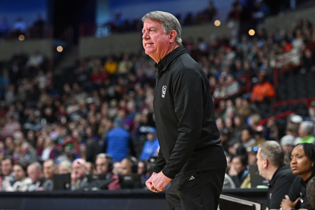 Wes Moore tenses his arms and makes two fists at his sides as he stands in front of assistant coaches.