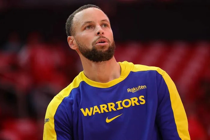 Person in Warriors jersey focused, preparing for basketball game