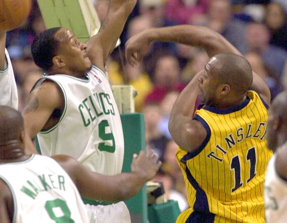 Jamaal Tinsley (R) of the Indiana Pacers passes over J.R. Bremer (L) of the Boston Celtics at the Fleet Center in Boston, Massachusetts, 26 February 2003. AFP PHOTO/JOHN MOTTERN (Photo by JOHN MOTTERN / AFP) (Photo by JOHN MOTTERN/AFP via Getty Images)