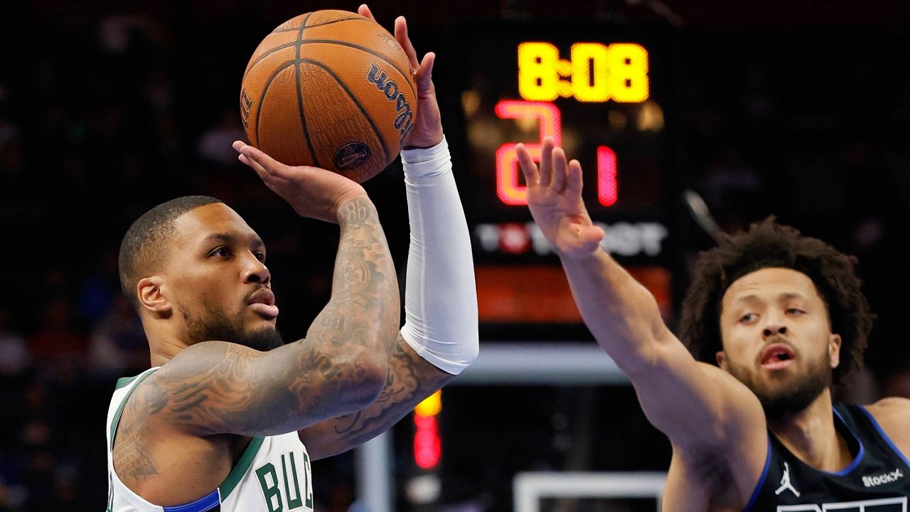 Milwaukee Bucks guard Damian Lillard takes a shot ahead of Detroit Pistons guard Cade Cunningham