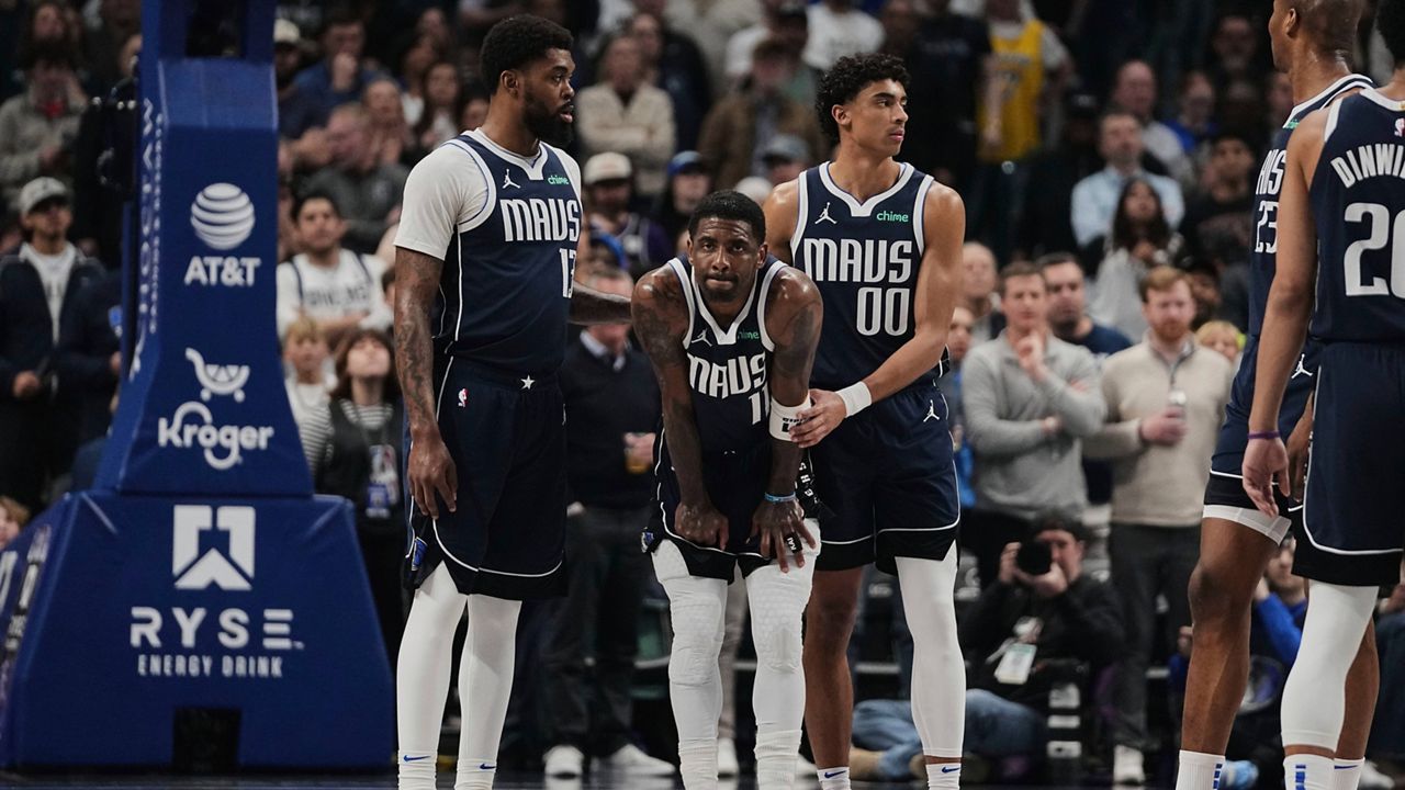 Dallas Mavericks' Naji Marshall (13), left, and Max Christie (00) stand by Kyrie Irving (11), center, after Irving shot free throws after suffering an injury in the first half of an NBA basketball game against the Sacramento Kings in Dallas, Monday, March 3, 2025. (AP Photo/Tony Gutierrez)