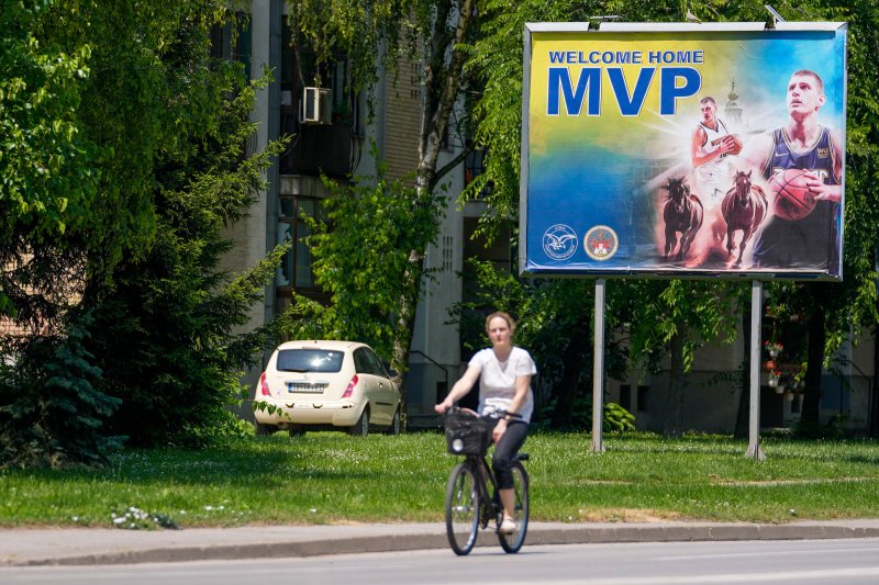 A woman rides a bicycle past a billboard showing Denver Nuggets center Nikola Jokic in his hometown of Sombor, Serbia, on June 18, 2023.