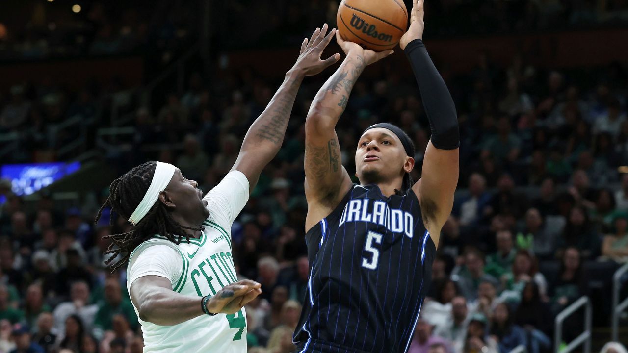 Orlando Magic's Paolo Banchero (5) shoots against Boston Celtics' Jrue Holiday (4) during the second half in Game 1 of a first-round NBA playoff basketball series Sunday, April 20, 2025, in Boston. (AP Photo/Michael Dwyer)