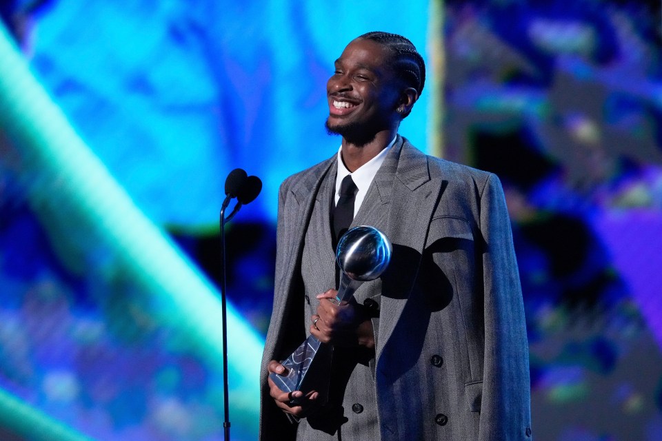 Shai Gilgeous-Alexander smiling and holding an award.