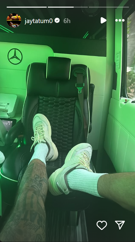Person's legs and feet in sneakers inside a luxury vehicle.