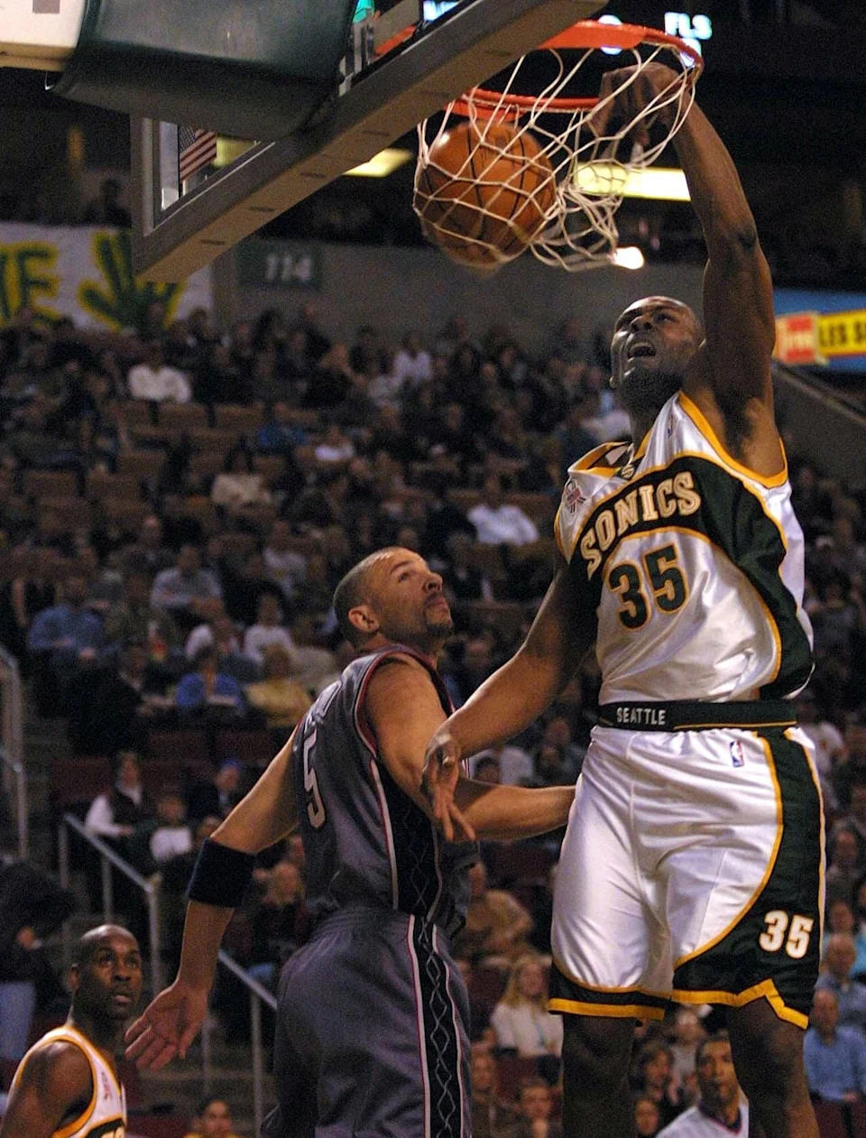 SEATTLE, UNITED STATES: Seattle Supersonics Art Long (R) dunks over New Jersey Nets Jason Kidd (C) as Gary Payton (L) looks on during first quarter action of their game in Seattle on 09 March 2002. AFP PHOTO/Dan LEVINE (Photo credit should read DAN LEVINE/AFP via Getty Images)