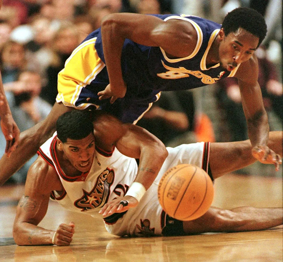 PHILADELPHIA, UNITED STATES: The Los Angeles Lakers' Kobe Bryant (top) flips over the Philadelphia 76'ers Jim Jackson as the two struggle for the loose rebound during their game 28 November in Philadelphia, PA. The 76'ers won 105-95. AFP PHOTO / Tom MIHALEK (Photo credit should read TOM MIHALEK/AFP via Getty Images)
