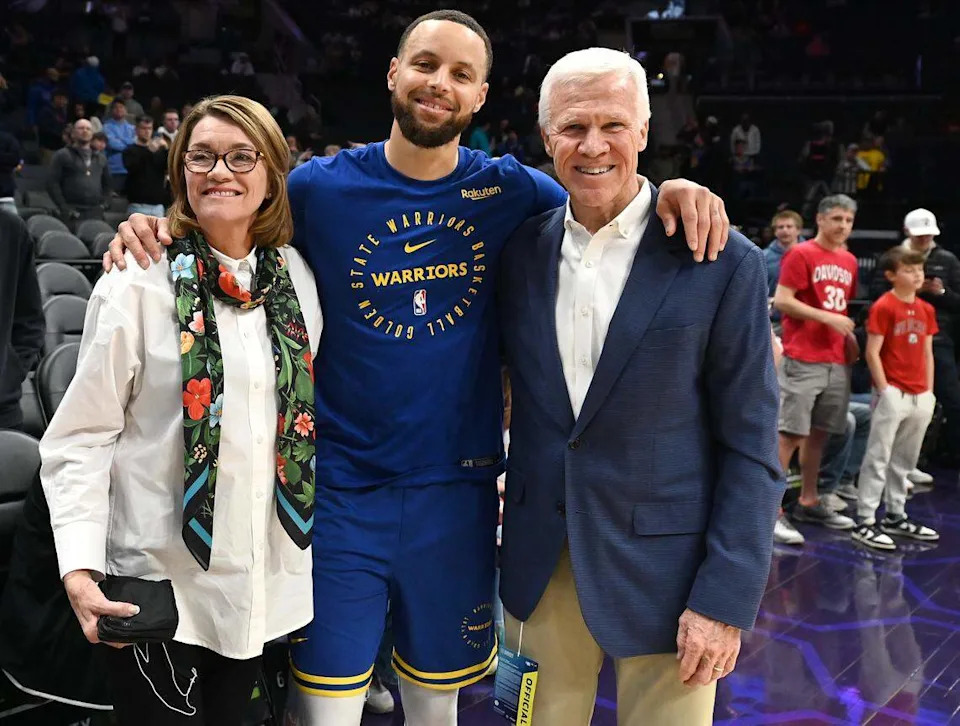 Golden State Warriors and former Davidson Wildcats star Steph Curry, center, poses for a photograph with Cathy and Bob McKillop courtside at Spectrum Center in Charlotte, NC on Monday, March 3, 2025.