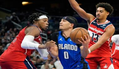 Orlando Magic guard Anthony Black (0) drives to the basket between Washington Wizards forward Richaun Holmes, left, and guard Jordan Poole (13) during the second half of an NBA basketball game, Sunday, Feb. 23, 2025, in Orlando, Fla. (AP Photo/John Raoux)