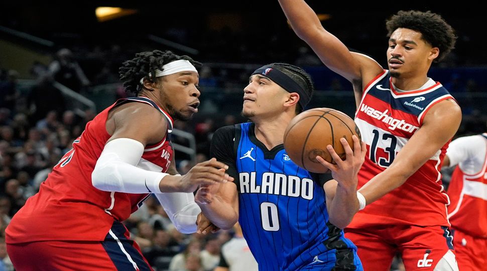 Orlando Magic guard Anthony Black (0) drives to the basket between Washington Wizards forward Richaun Holmes, left, and guard Jordan Poole (13) during the second half of an NBA basketball game, Sunday, Feb. 23, 2025, in Orlando, Fla. (AP Photo/John Raoux)