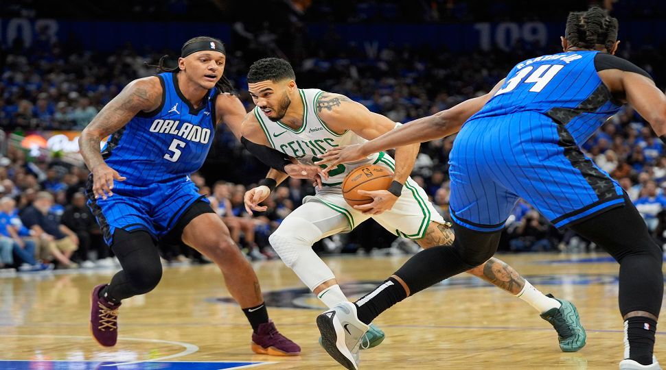 Boston Celtics forward Jayson Tatum, center, drives between Orlando Magic forward Paolo Banchero (5) and center Wendell Carter Jr. (34) during the first half in Game 4 of a first-round NBA basketball playoff series, Sunday, April 27, 2025, in Orlando, Fla. (AP Photo/John Raoux)