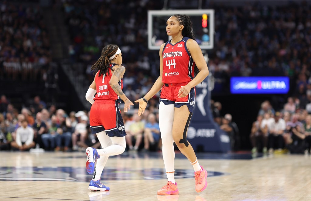 Washington Mystics forward Kiki Iriafen extends her right hand to high-five guard Sug Sutton. Iriafen is facing the camera, while Sutton is running the other way.