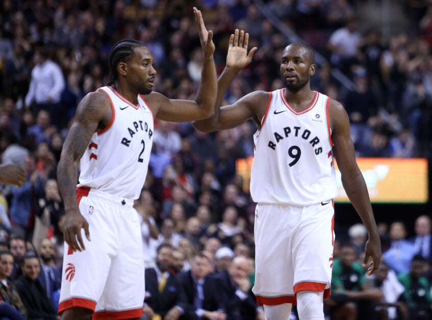 Kawhi Leonard #2 and Serge Ibaka #9 of the Toronto Raptors react late in the second half of an NBA game against the Boston Celtics at Scotiabank Arena.
