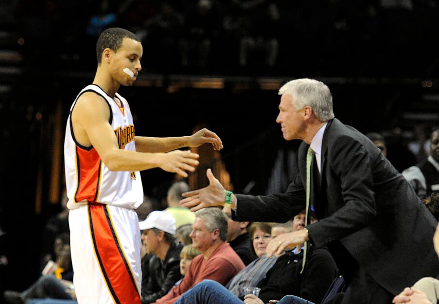 Golden State Warriors' Stephen Curry reaches to shake hands and hug former coach, Davidson's Bob McKillop, prior to tipoff of the Warriors' game against the Charlotte Bobcats.