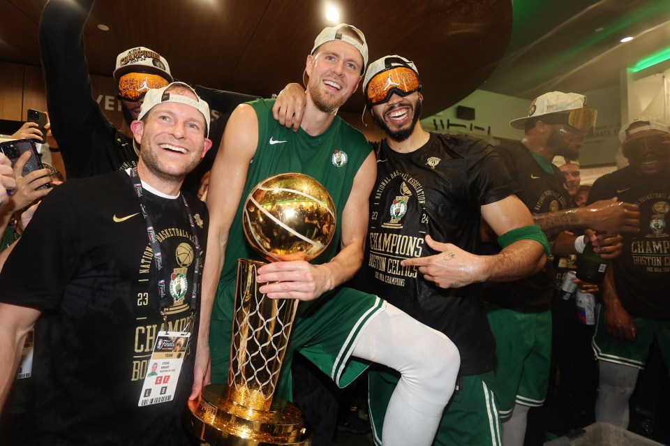 BOSTON, MASSACHUSETTS - JUNE 17: Kristaps Porzingis #8 and Jayson Tatum #0 of the Boston Celtics celebrate with the Larry O’Brien Championship Trophy in the locker room after Boston's 106-88 win against the Dallas Mavericks in Game Five of the 2024 NBA Finals at TD Garden on June 17, 2024 in Boston, Massachusetts. NOTE TO USER: User expressly acknowledges and agrees that, by downloading and or using this photograph, User is consenting to the terms and conditions of the Getty Images License Agreement. (Photo by Elsa/Getty Images)