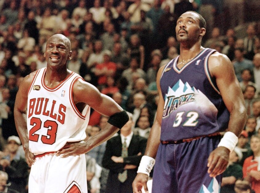 Michael Jordan (L) of the Chicago Bulls smiles while standing next to Karl Malone of the Utah Jazz 07 June in the first half of game three of the NBA Finals at the United Center in Chicago, IL. The seven game series is tied at 1-1.