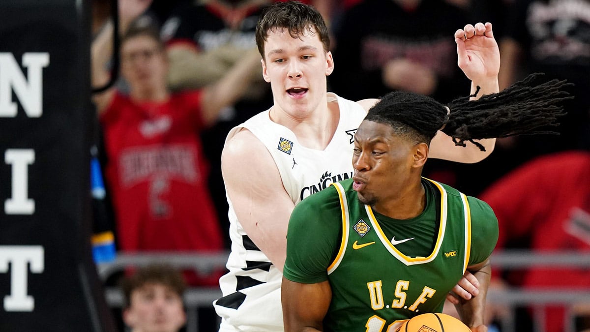 San Francisco Dons forward Jonathan Mogbo (10) spins toward the basket as Cincinnati Bearcats guard Simas Lukosius (41) defends in the second half of a college basketball game in the National Invitation Tournament, Wednesday, March 20, 2024, at Fifth Third Arena in Cincinnati.