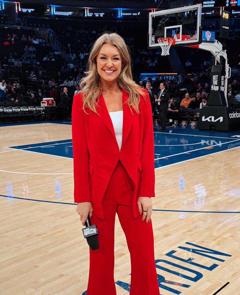 Katy Winge on a basketball court holding a microphone