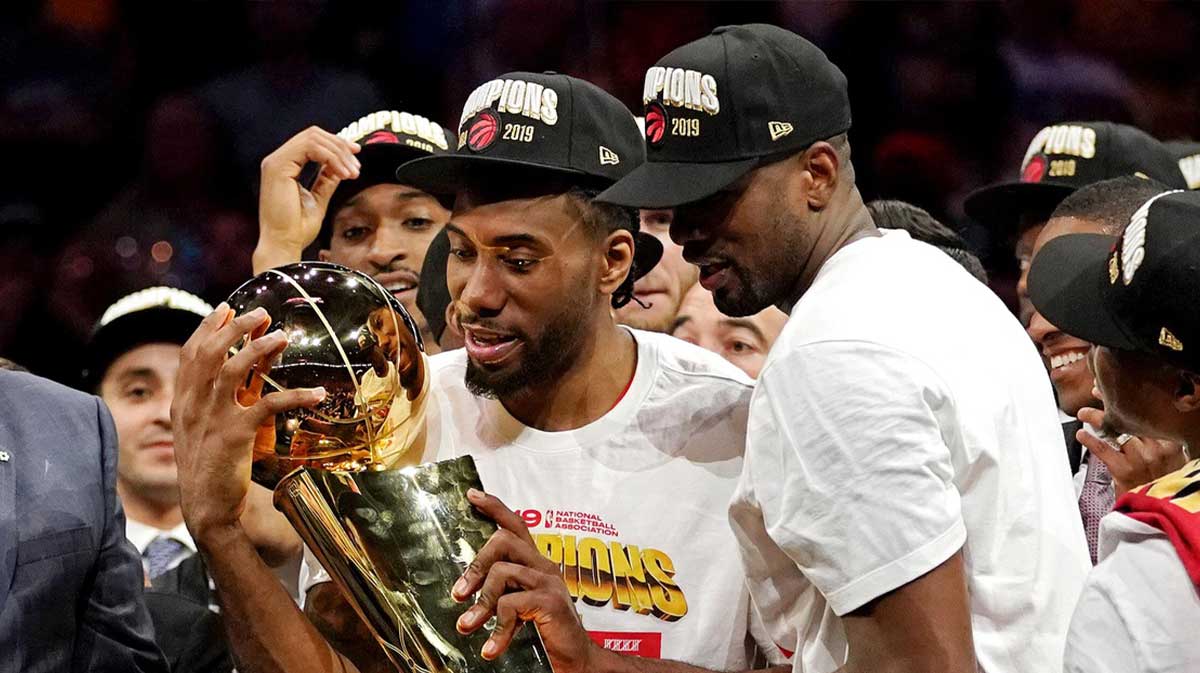 Toronto Raptors forward Kawhi Leonard (2) and Toronto Raptors center Serge Ibaka (9) celebrate with the Larry O'Brien Trophy after the Golden State Warriors in game six of the 2019 NBA Finals at Oracle Arena.