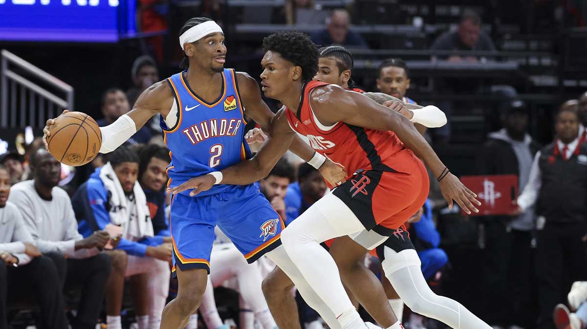 Oklahoma City Thunder guard Shai Gilgeous-Alexander (2) controls the ball as Houston Rockets forward Amen Thompson (1) defends during the game at Toyota Center.