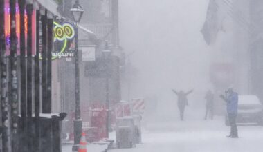 People walk around on Bourbon Street as snow falls in the French Quarter in New Orleans, Tuesday, Jan. 21, 2025.