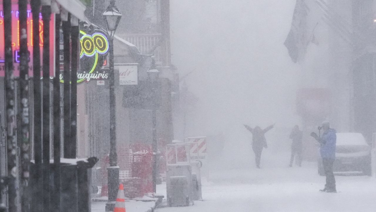 People walk around on Bourbon Street as snow falls in the French Quarter in New Orleans, Tuesday, Jan. 21, 2025.