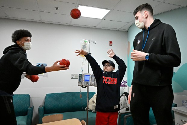 UConn's Jaylin Stewart, left, and Donovan Clingan, right, play hoops with cancer patient Elijah Randolph, 11, center, of Farmington during a visit with their team to the Connecticut Children's Center for Cancer and Blood Disorders, in Hartford, Conn., Wednesday, Jan. 24, 2024. The team will honor all those who have been affected by cancer in this Sunday's "Coaches vs. Cancer" game against Xavier. (Jessica Hill/Special to the Courant)