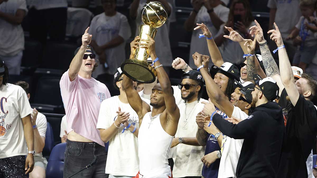 Thunder guard Shai Gilgeous-Alexander (2) holds up the Larry OíBrien Championship Trophy during the Champions Opening Ceremony for the parade inside the Paycom Center with Thunder regular season schedule in the background