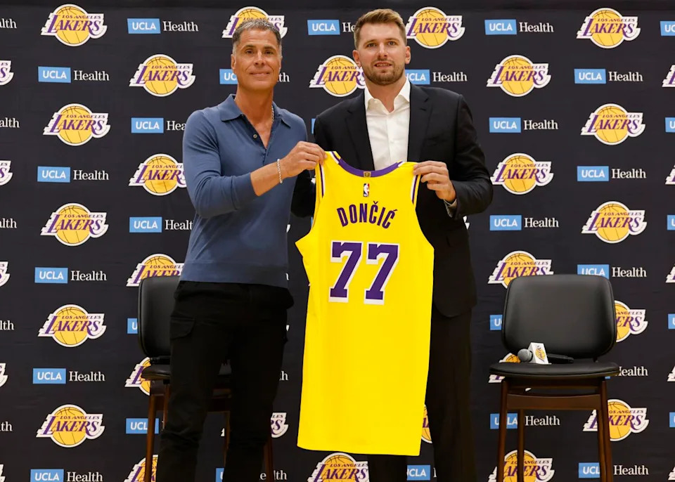 Lakers general manager Rob Pelinka, left, and Luka Doncic hold up Doncic's jersey.