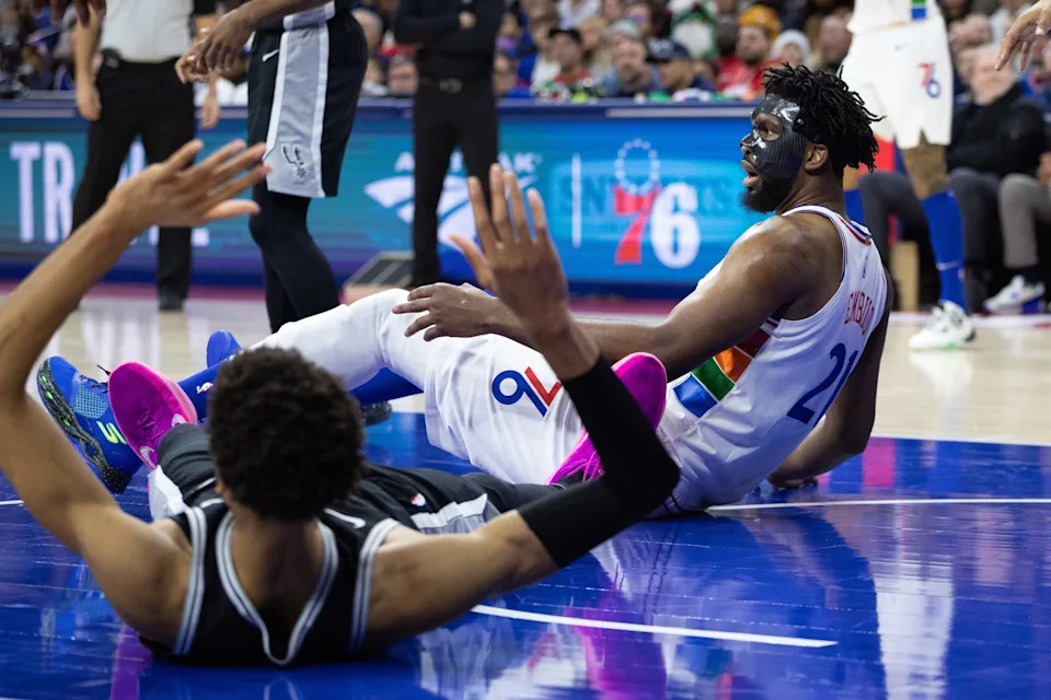 Dec 23, 2024; Philadelphia, Pennsylvania, USA; Philadelphia 76ers center Joel Embiid (21) and San Antonio Spurs center Victor Wembanyama (1) fall to the floor after colliding during the second quarter at Wells Fargo Center. Mandatory Credit: Bill Streicher-Imagn Images