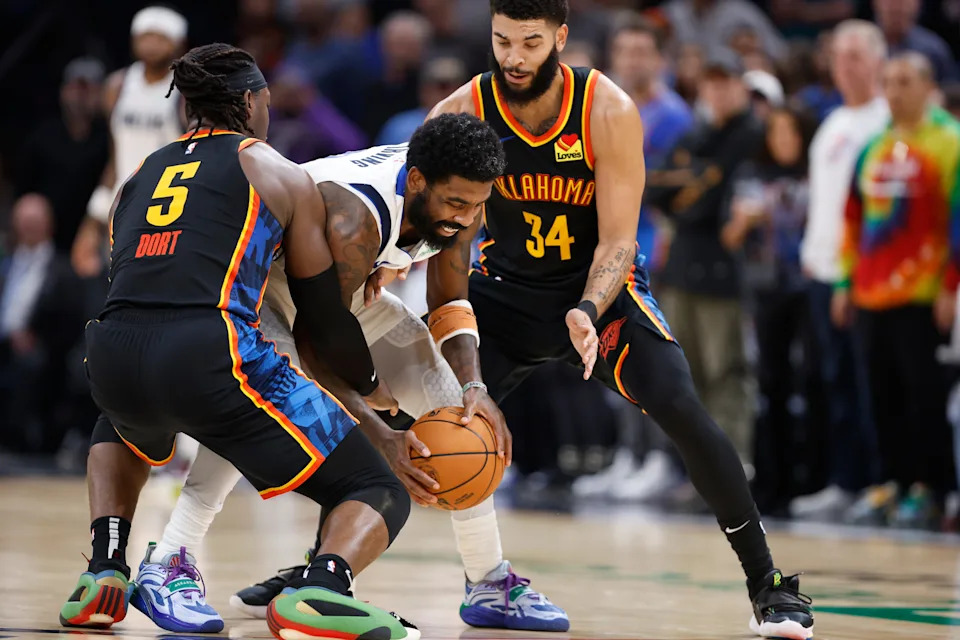 Nov 17, 2024; Oklahoma City, Oklahoma, USA; Dallas Mavericks guard Kyrie Irving (11) moves the ball between Oklahoma City Thunder guard Luguentz Dort (5) and forward Kenrich Williams (34) during the second half at Paycom Center. Mandatory Credit: Alonzo Adams-Imagn Images