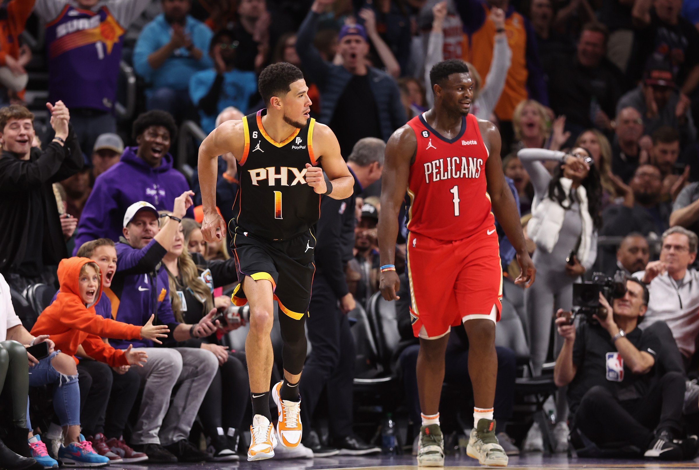 PHOENIX, ARIZONA - DECEMBER 17: Devin Booker #1 of the Phoenix Suns reacts to a three-point shot over Zion Williamson #1 of the New Orleans Pelicans during the second half of the NBA game at Footprint Center on December 17, 2022 in Phoenix, Arizona. The Suns defeated the Pelicans 118-114. NOTE TO USER: User expressly acknowledges and agrees that, by downloading and or using this photograph, User is consenting to the terms and conditions of the Getty Images License Agreement. (Photo by Christian Petersen/Getty Images)
