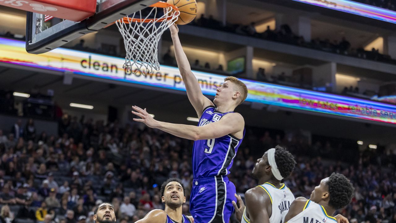 kevin huerter, in purple sacramento kings uniform, goes up for a layup as other players watch during an nba game