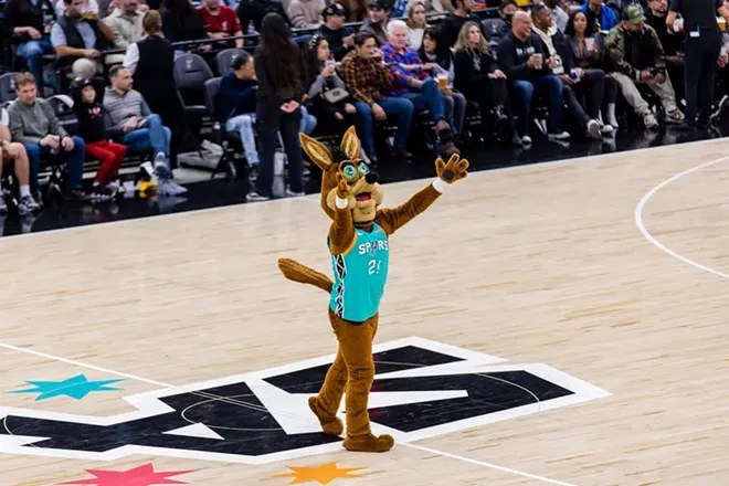 The Spurs Coyote raises its paws on the basketball court to get the crowd hyped.