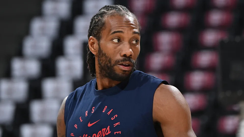 A basketball player with braided hair wearing a navy sleeveless