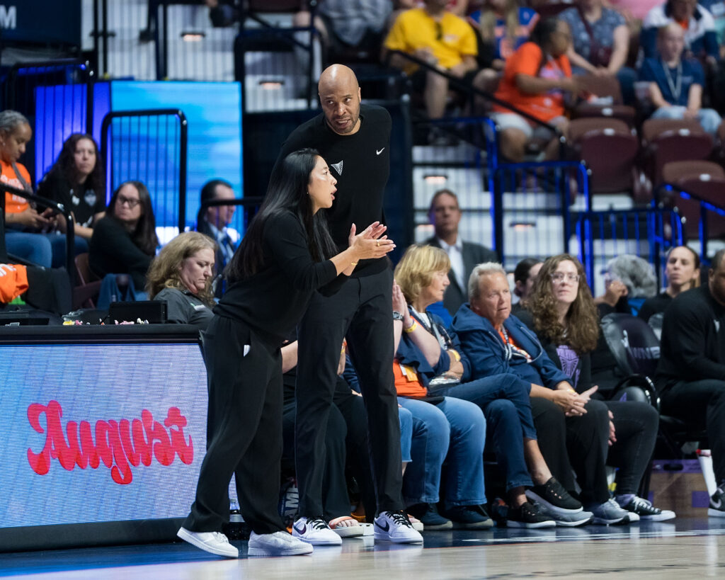 Golden State Valkyries assistant coach Kasib Powell speaks with head coach Natalie Nakase on the sideline during a game.