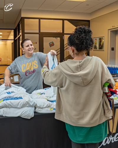 Cleveland Cavaliers volunteer handing out bags of food to members of the community.