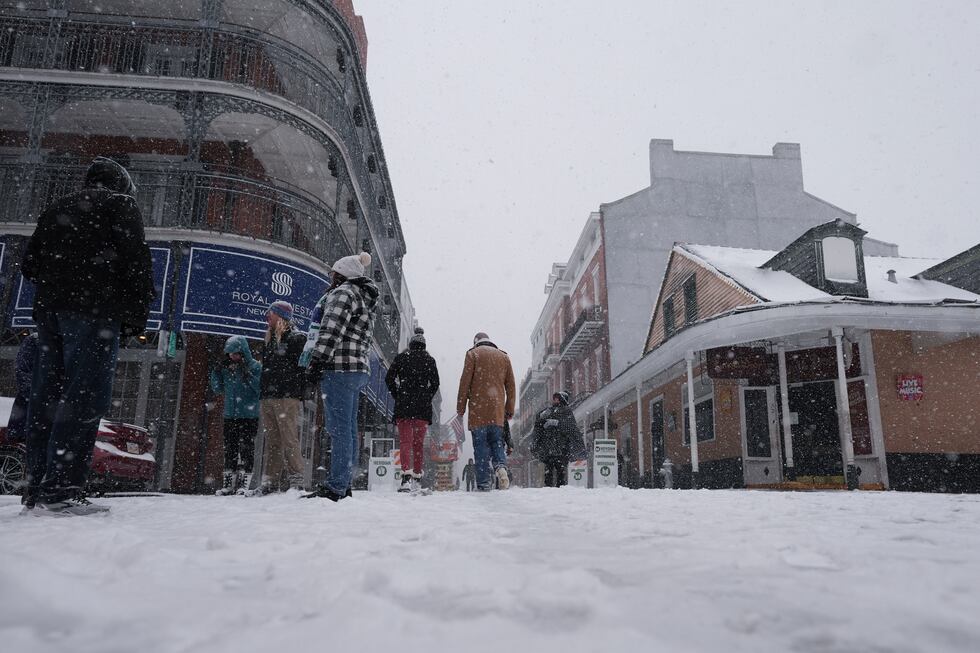 People walk in the French Quarter as snow falls in New Orleans, Tuesday, Jan. 21, 2025. (AP...