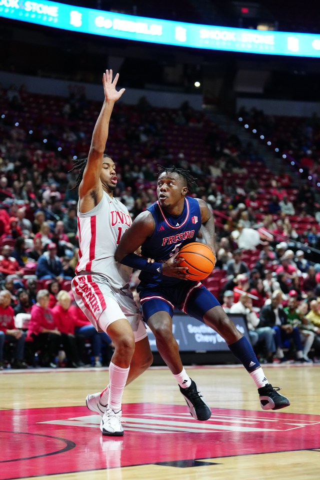 Fresno State Bulldogs player driving to the basket, defended by a UNLV Rebels player.