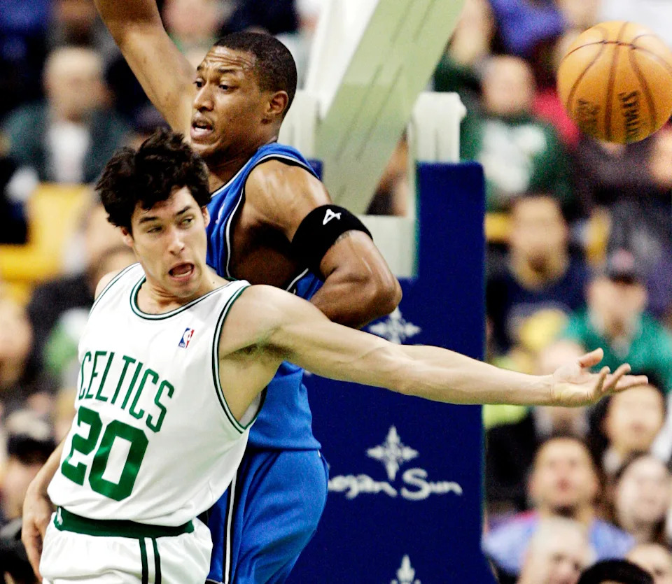 The Boston Celtics' Dan Dickau (L) passes the ball around the Orlando Magic's Tony Battie in second quarter NBA action in Boston, Massachusetts November 28, 2005. REUTERS/Brian Snyder