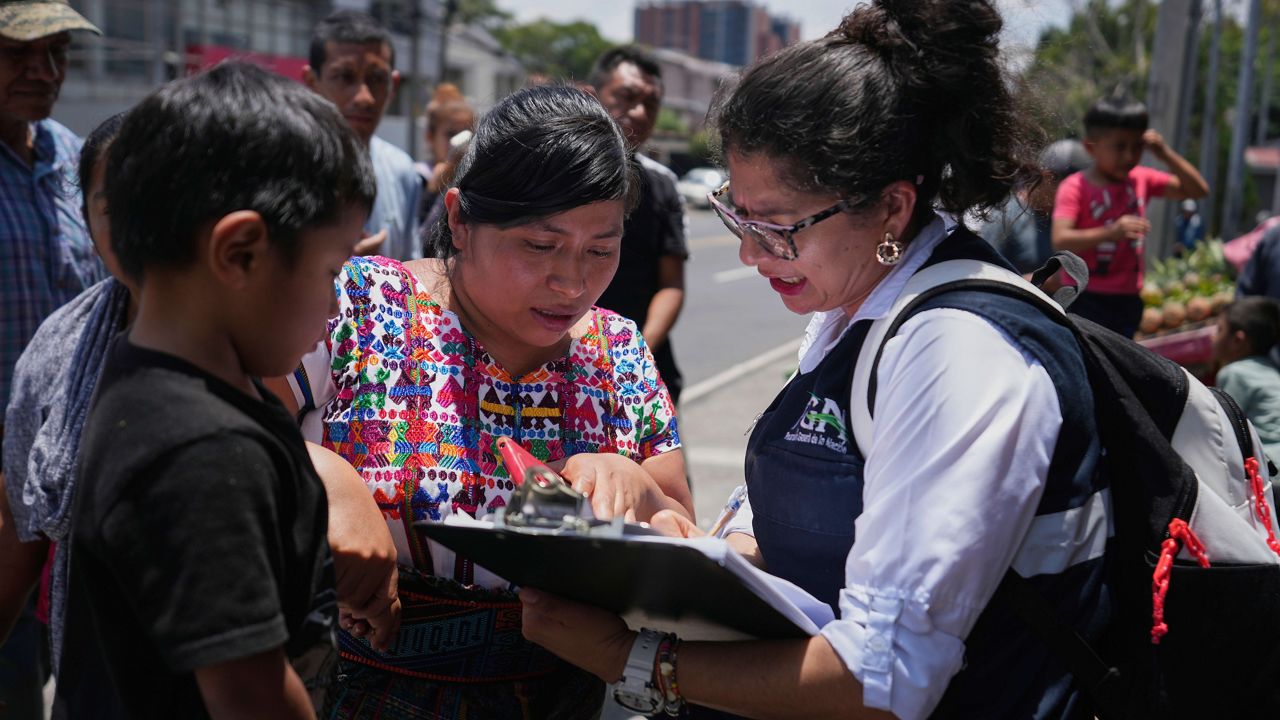 A relative of an unaccompanied minor deported from the United States reviews the list of those deported outside La Aurora International Airport, in Guatemala City, Sunday, Aug. 31, 2025. (AP Photo/Moises Castillo)