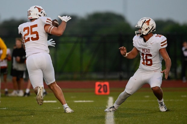 Mead’s Ethan Elmore, right, pitches the ball to Griffin Kratochvil,...