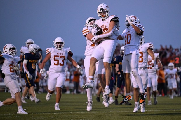 Mead’s Eli Davis, center, celebrates his touchdown with Liam Roberts,...