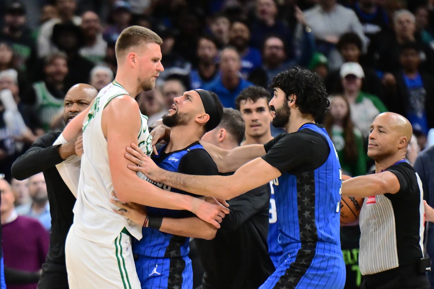 Orlando's Jalen Suggs jumps between teammate Goga Bitadze (right) and Celtics center Kristaps Porzingis (left) in a scuffle in the fourth quarter Monday night. Bitadze was ejected following the sequence, while Suggs and Porzingis got technicals. 