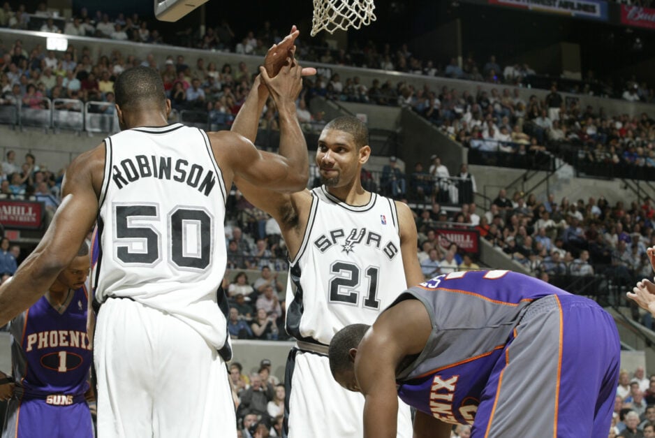 San Antonio Spurs legends David Robinson and Tim Duncan celebrating a play with a high-five.