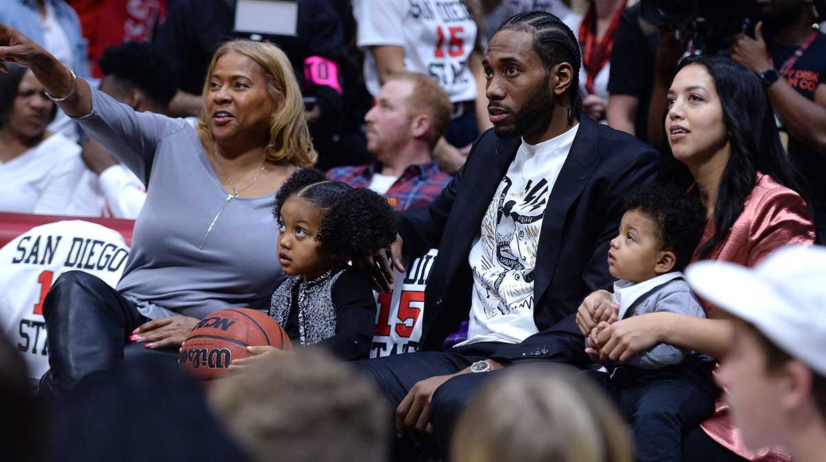 San Diego State Aztecs former player Kawhi Leonard (C) and family watch the game between the Aztecs and Utah State Aggies during the first half at Viejas Arena.