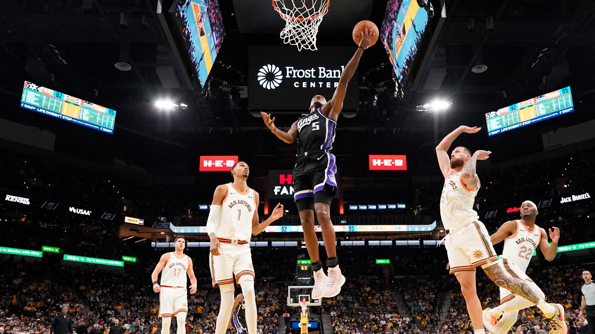 Sacramento Kings guard De'Aaron Fox (5) drives to the basket between San Antonio Spurs forwards Victor Wembanyama (1) and Sandro Mamukelashvili (54) during the second half at Frost Bank Center. 