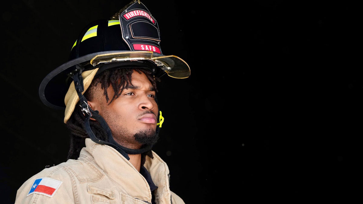 Spurs' guard Stephon Castle at USAA event in firefighter outfit.